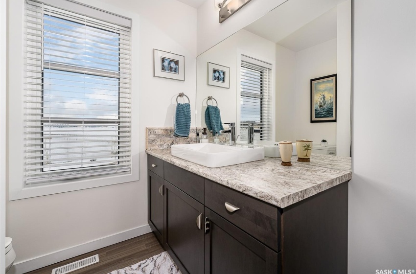 Bathroom with hardwood / wood-style flooring, vanity with extensive cabinet space, and toilet