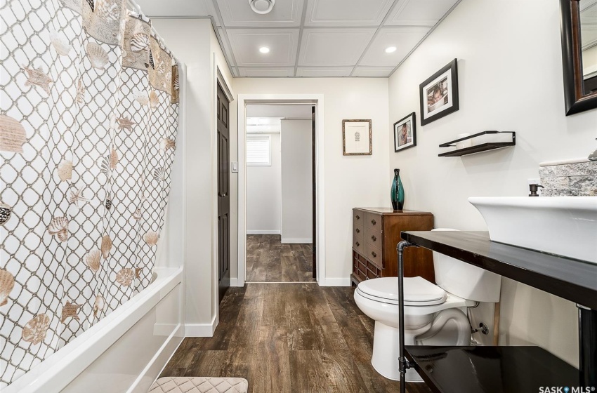 Bathroom with shower / bath combo, hardwood / wood-style floors, and toilet