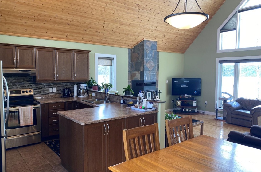 Kitchen featuring stainless steel electric range oven, sink, hanging light fixtures, wood ceiling, and high vaulted ceiling