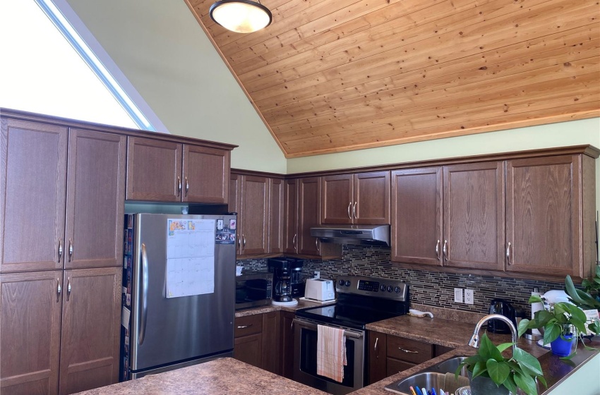 Kitchen with high vaulted ceiling, stainless steel appliances, wooden ceiling, sink, and tasteful backsplash