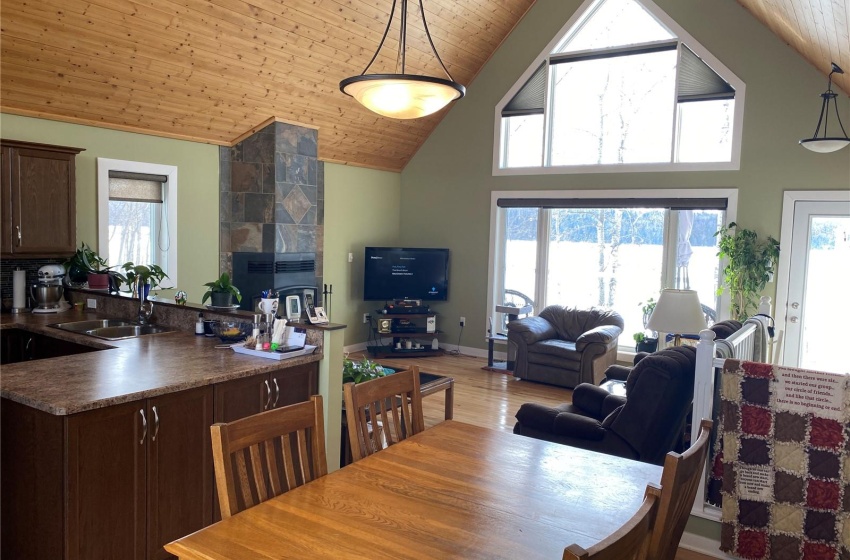 Dining area featuring high vaulted ceiling, a tile fireplace, wooden ceiling, sink, and light wood-type flooring