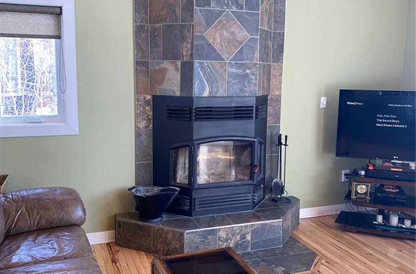 Living room with a tile fireplace, wood ceiling, tile walls, and light hardwood / wood-style flooring