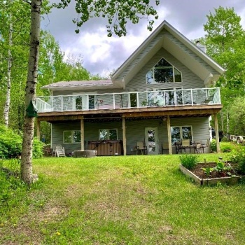 Rear view of property featuring a yard and a hot tub