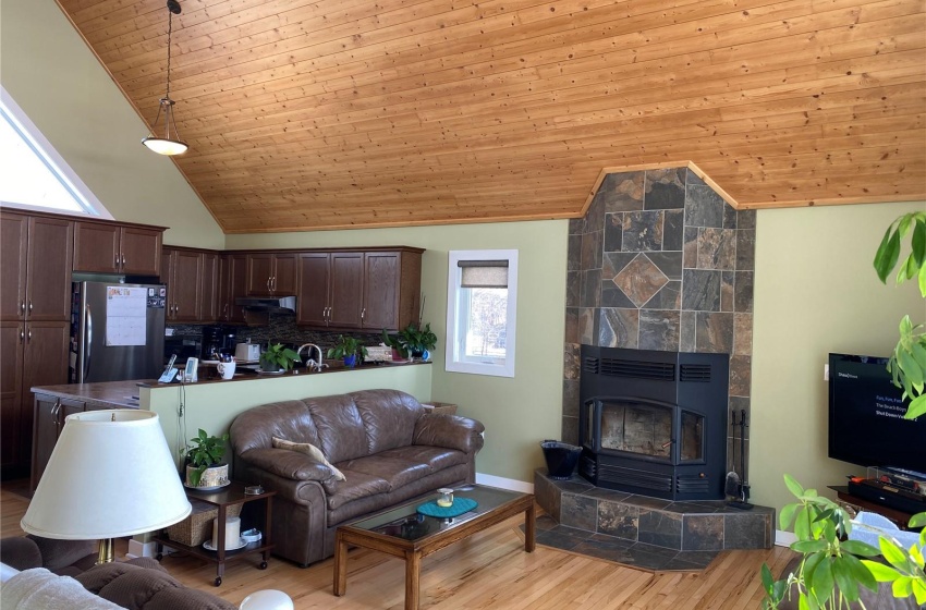 Living room with a tile fireplace, light wood-type flooring, wooden ceiling, and high vaulted ceiling