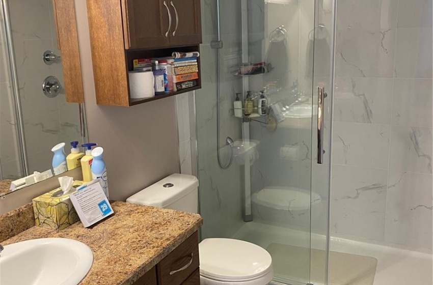 Bathroom featuring vanity with extensive cabinet space, a shower with door, tile flooring, and toilet