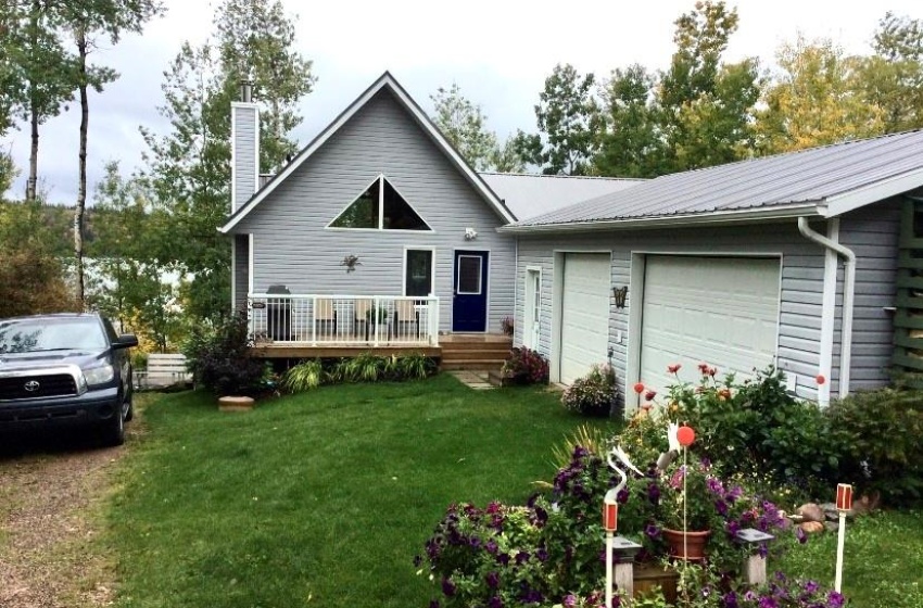 Back of property with a lawn, a wooden deck, and a garage