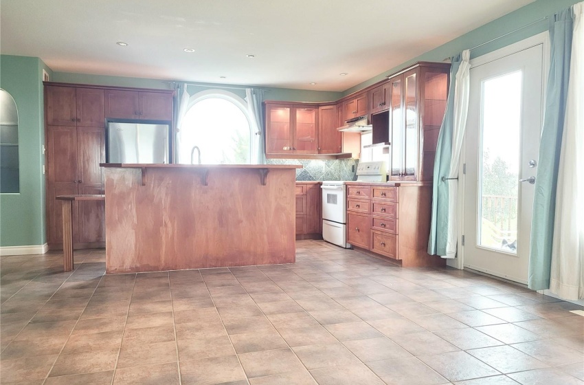 Kitchen featuring backsplash, a kitchen bar, white electric range oven, light tile floors, and fridge