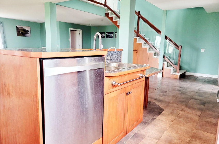 Kitchen featuring granite tile countertops, raised dishwasher, and sink