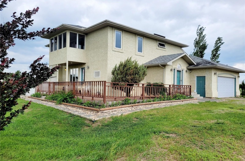 Front facade with a deck, a front yard, and a garage