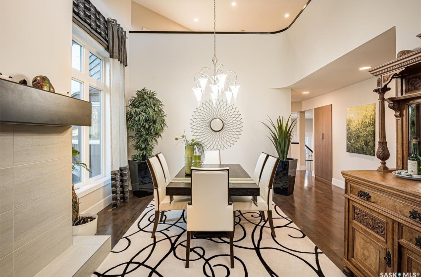 Dining room featuring a towering ceiling, a notable chandelier, a healthy amount of sunlight, and dark hardwood / wood-style floors