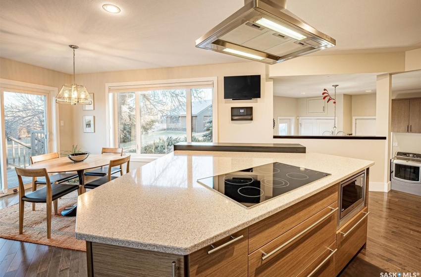 Kitchen featuring stainless steel appliances, a notable chandelier, dark hardwood / wood-style floors, a kitchen island, and island range hood