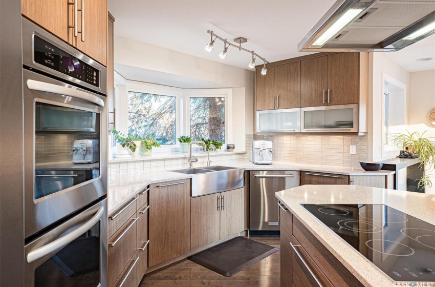 Kitchen featuring dark wood-type flooring, rail lighting, sink, appliances with stainless steel finishes, and backsplash