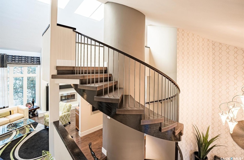 Custom circular staicase featuring dark hardwood / wood-style floors and a towering ceiling