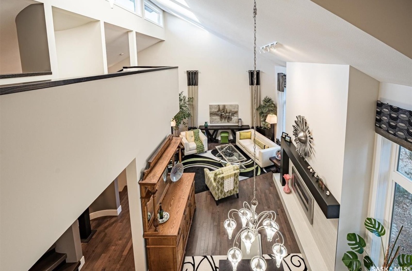 Living room featuring a towering ceiling, a notable chandelier, and hardwood  flooring