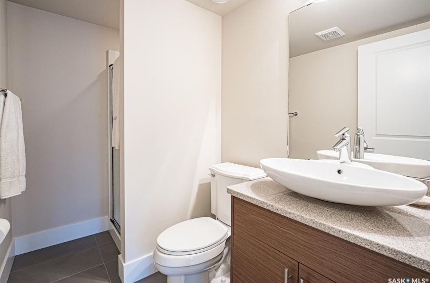 Bathroom featuring toilet, tile floors, a shower with door, and vanity