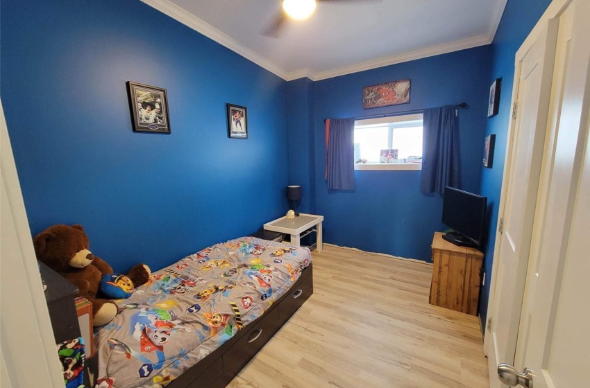 Bedroom with light hardwood / wood-style floors, ceiling fan, and ornamental molding