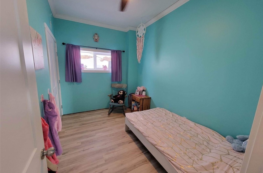 Bedroom featuring light hardwood / wood-style floors, ceiling fan, and ornamental molding