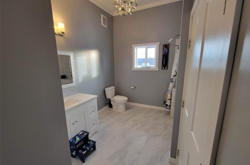 Bathroom featuring a chandelier, toilet, vanity, crown molding, and tile floors