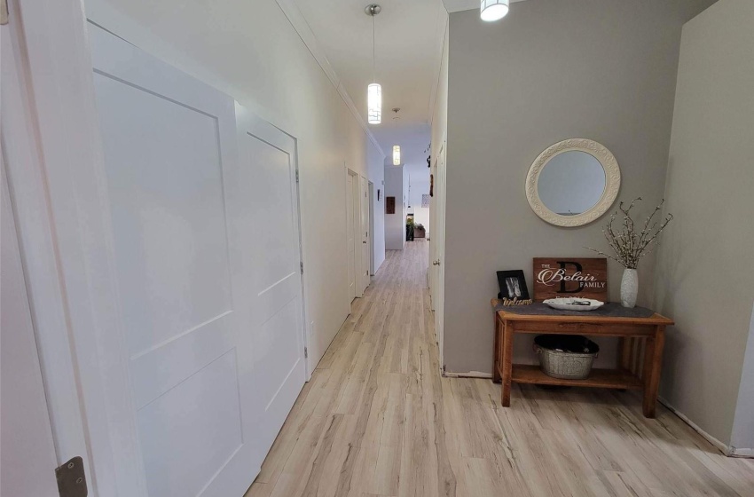 Hall with ornamental molding and light hardwood / wood-style flooring