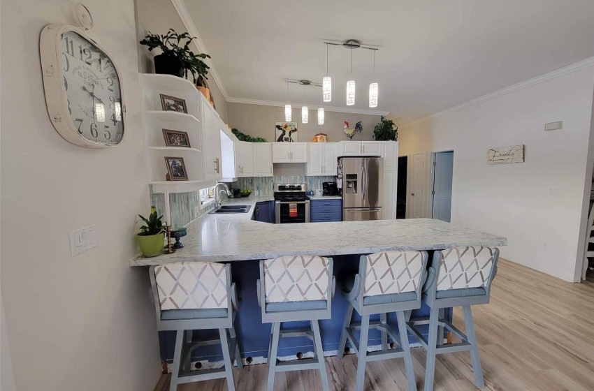 Kitchen with kitchen peninsula, sink, light hardwood / wood-style floors, stainless steel appliances, and tasteful backsplash