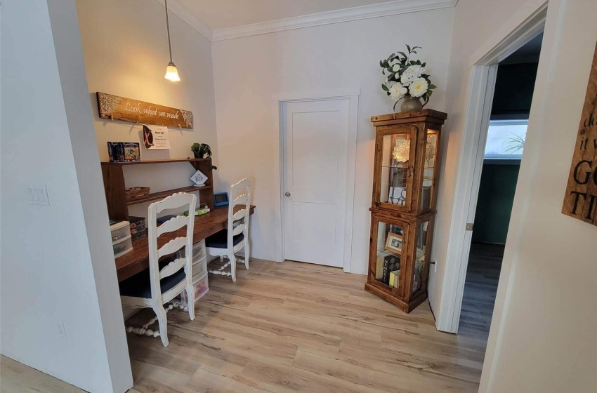 Office area with light hardwood / wood-style floors and crown molding