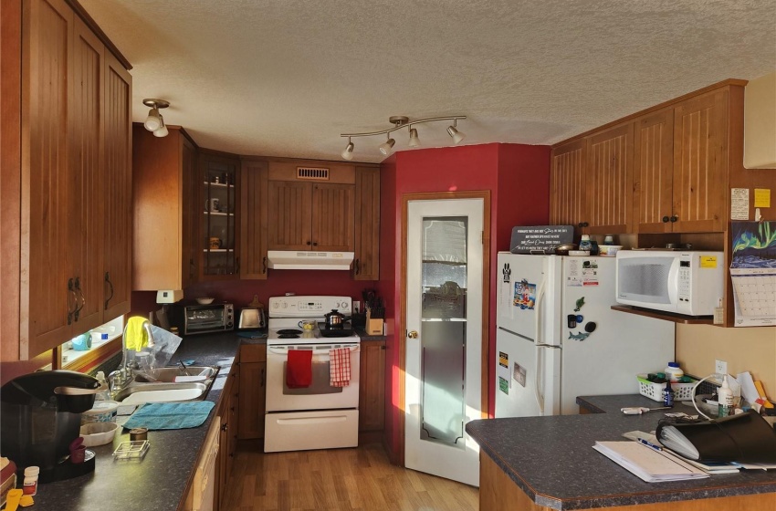 Kitchen featuring light hardwood / wood-style floors, white appliances, a textured ceiling, and track lighting