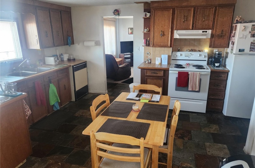 Kitchen with white appliances, backsplash, a textured ceiling, sink, and dark tile floors