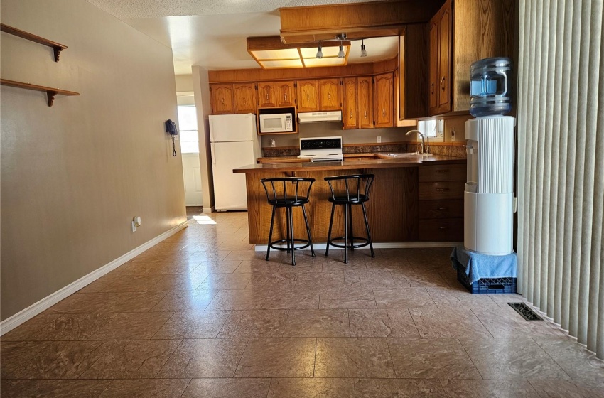 Kitchen/Dining Area with a kitchen bar, a textured ceiling, white appliances, dark tile floors, and sink