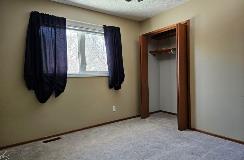 3rd bedroom with ceiling fan, a textured ceiling, and light colored carpet