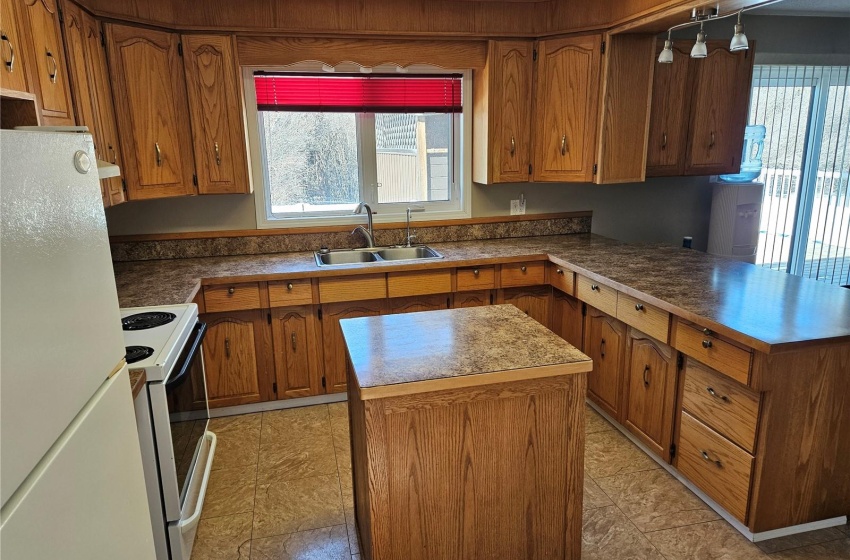 Kitchen with white appliances, a kitchen island, sink, and light tile floors