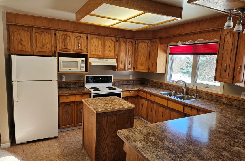 Kitchen featuring white appliances, sink, light tile floors, and a kitchen island