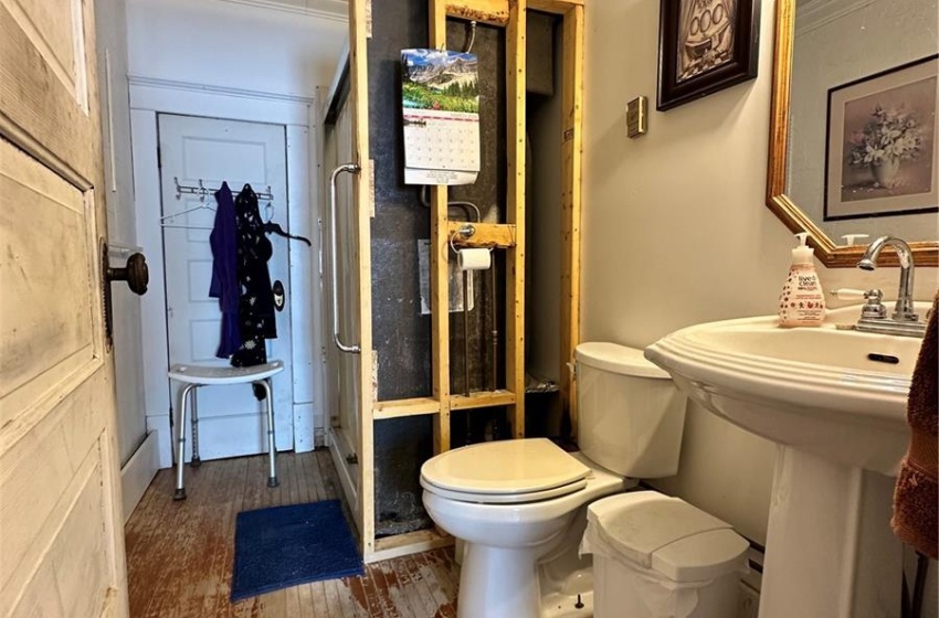 Bathroom featuring crown molding, toilet, a shower with door, hardwood / wood-style floors, and ceiling fan