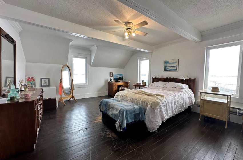 Bedroom with multiple windows, ceiling fan, dark hardwood / wood-style floors, and beam ceiling