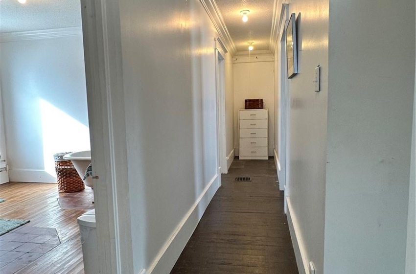 Corridor featuring ornamental molding and dark wood-type flooring