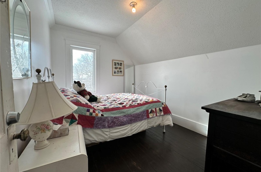 Bedroom with lofted ceiling, dark hardwood / wood-style floors, and a textured ceiling