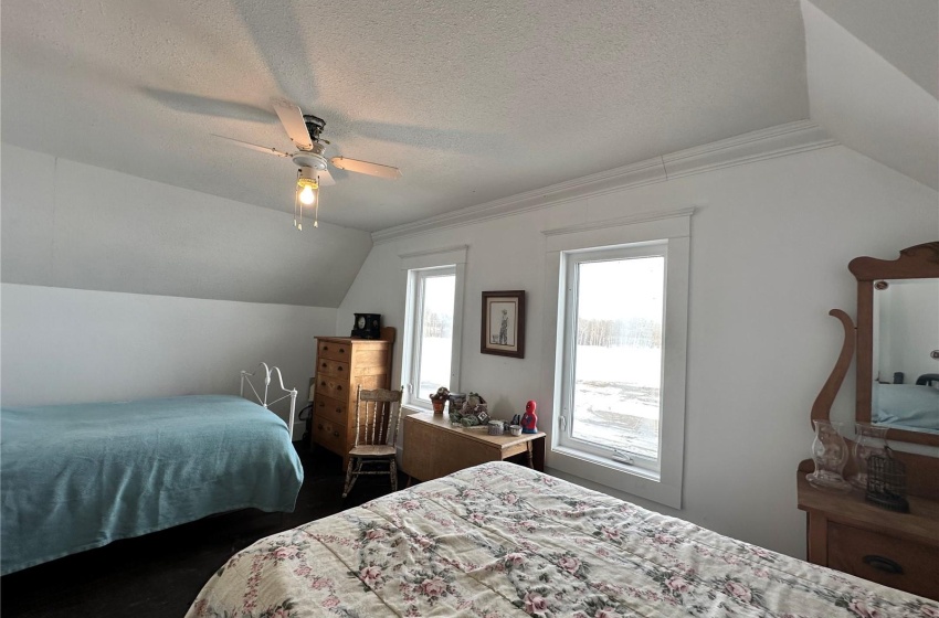 Bedroom with a textured ceiling, lofted ceiling, and ceiling fan