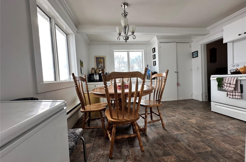 Tiled dining room with crown molding, an inviting chandelier, and baseboard heating