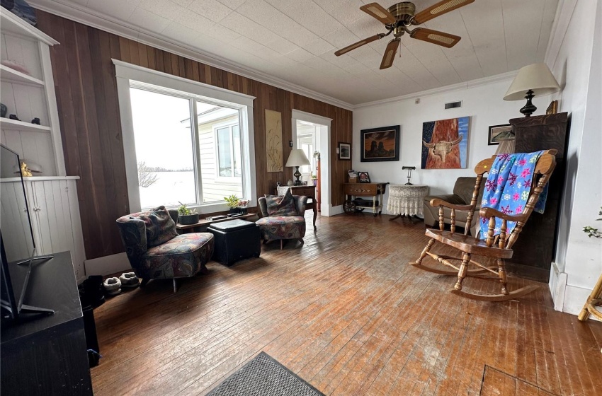 Living room with wooden walls, ceiling fan, crown molding, and hardwood / wood-style flooring