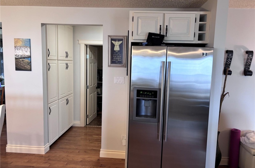 Kitchen featuring oak cabinets, stainless steel fridge with ice dispenser, a textured ceiling, and aged oak hardwood flooring