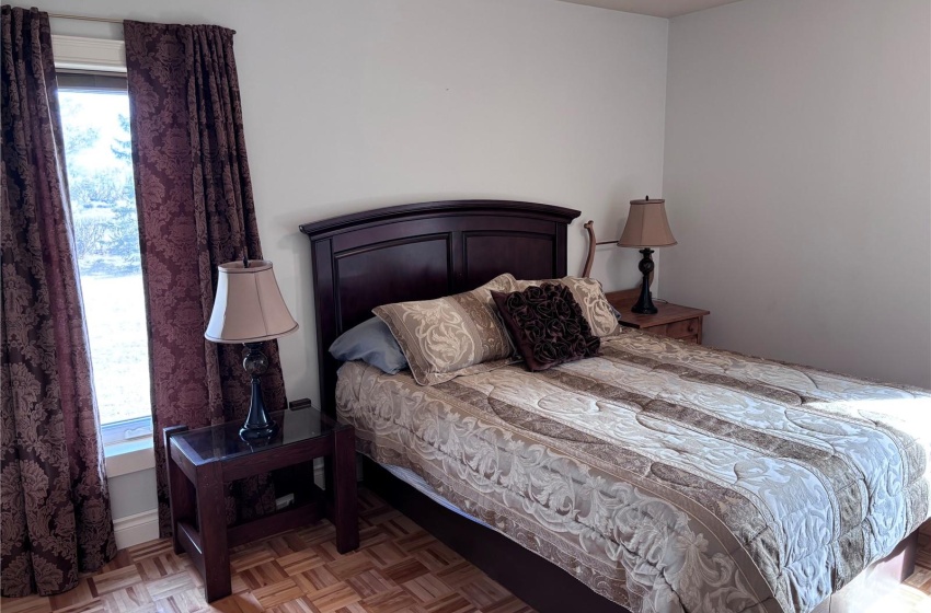 Main floor Bedroom with light parquet flooring and multiple windows