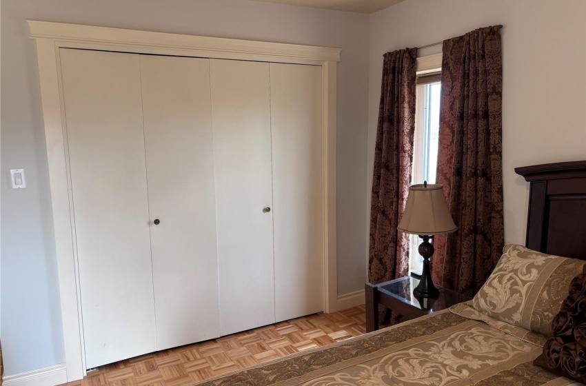 Main floor Bedroom with light parquet flooring and a closet