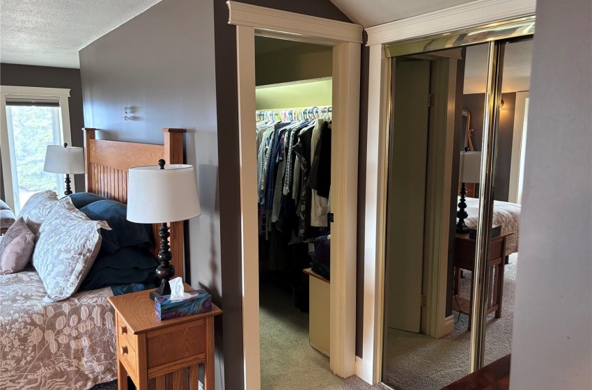 Primary bedroom with a walk in closet, light carpet,  and two regular closets