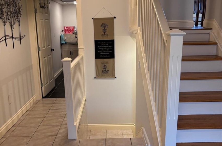 Stairway featuring light tile floors , access to laundry room straight ahead on the left