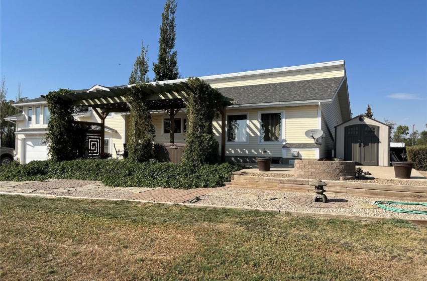 View of front of property with a front yard, a storage unit, and a pergola