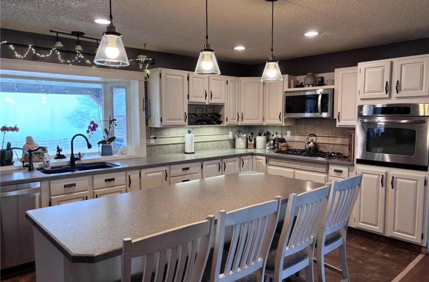 Kitchen featuring decorative light fixtures, appliances with stainless steel finishes, off white cabinets, backsplash, and sink