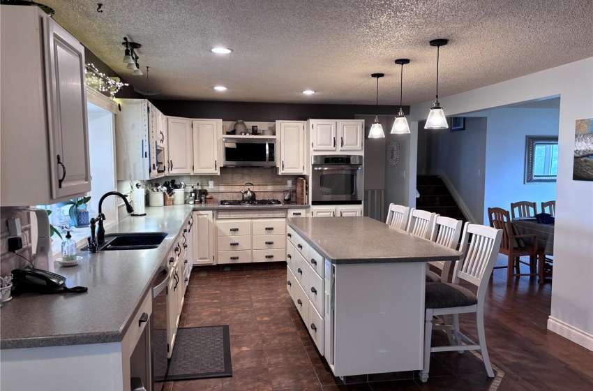 Kitchen with stainless steel appliances, a center island, off white cabinets, and hanging light fixtures