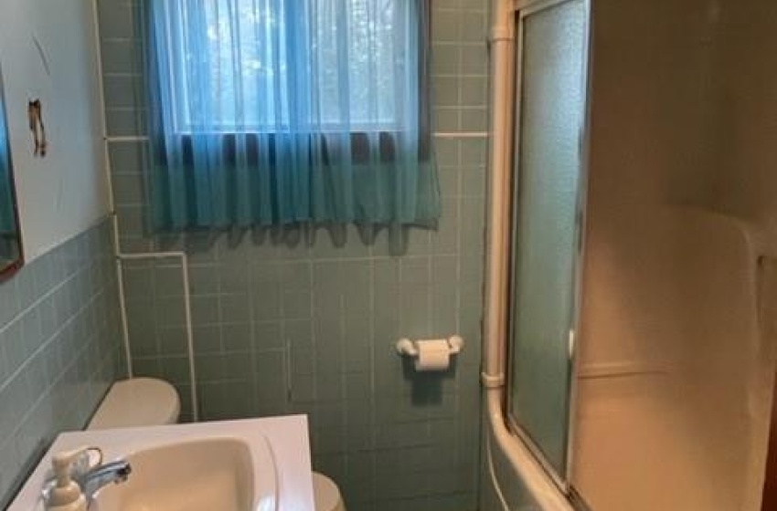 Full bathroom with tile walls, sink, tile flooring, bath / shower combo with glass door, and toilet