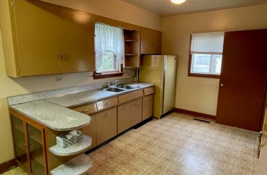 Kitchen featuring white refrigerator, sink, light tile floors, and plenty of natural light