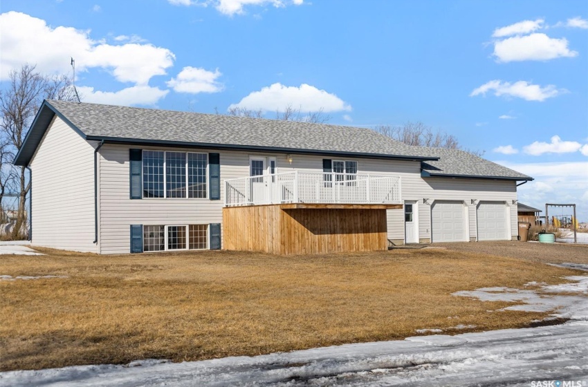 View of front of property with a wooden deck, a front lawn, and a garage