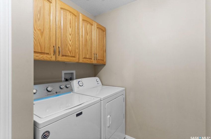 Washroom with washer hookup, cabinets, a textured ceiling, and washing machine and dryer